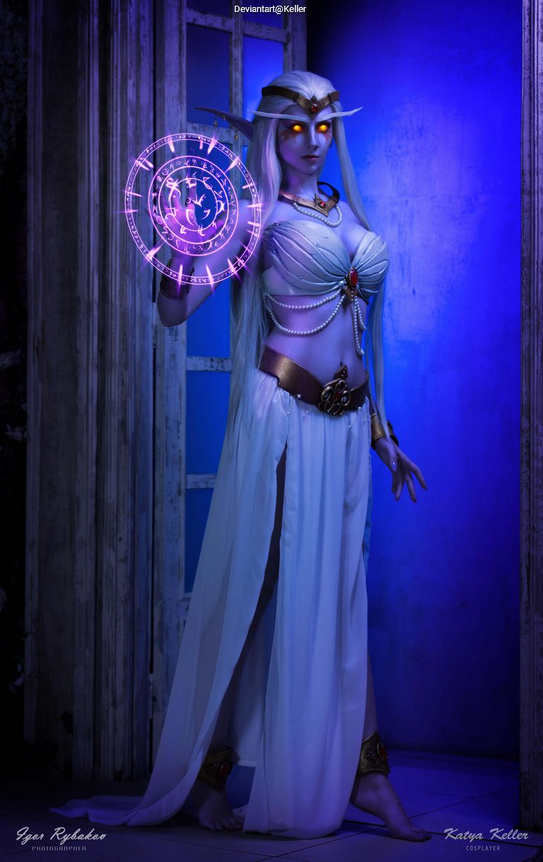 A female cosplayer dressed as a mystical character, wearing flowing white garments and elaborate accessories, holding a glowing purple magical symbol.