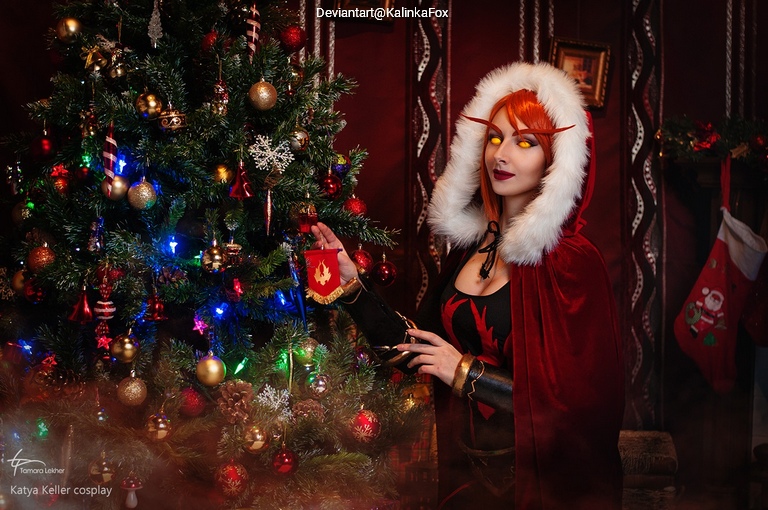 Cosplayer dressed as a fantasy character stands next to a decorated Christmas tree with colorful lights and ornaments.