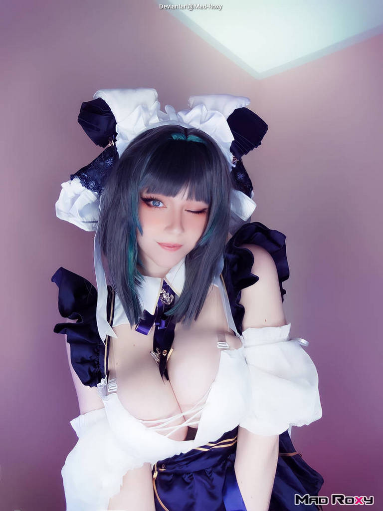 A smiling young woman with shoulder-length hair wearing a stylish maid outfit, featuring dark colors and intricate details, poses playfully with a wink against a softly lit background.