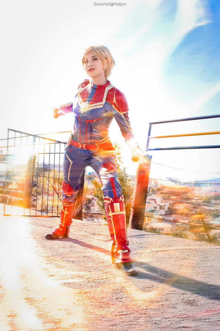 A person in a superhero costume poses dynamically outdoors, with a bright background and an energetic atmosphere.