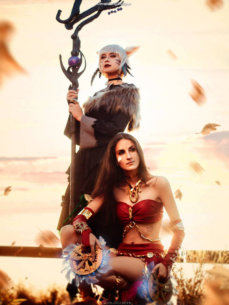 A fantasy-themed image featuring two female figures in elaborate costumes. One character stands tall with a staff, wearing a fur-lined outfit and cat-like ears, while the other is seated in a revealing red outfit adorned with jewelry and accessories. The background shows a sunset atmosphere with leaves drifting in the breeze.