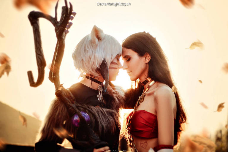 Two characters in a close embrace, with one wearing a black outfit and having cat-like features, and the other in a red outfit. The background is bright with warm light and falling leaves.