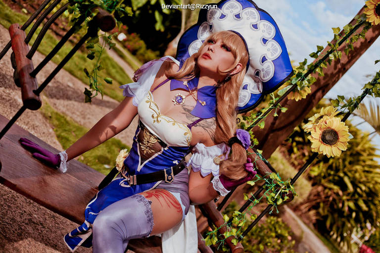 A person dressed in a detailed fantasy costume with a blue and white color scheme, sitting on a wooden swing surrounded by greenery and sunflowers. The character has long, blonde hair and is posing gracefully under a clear blue sky.