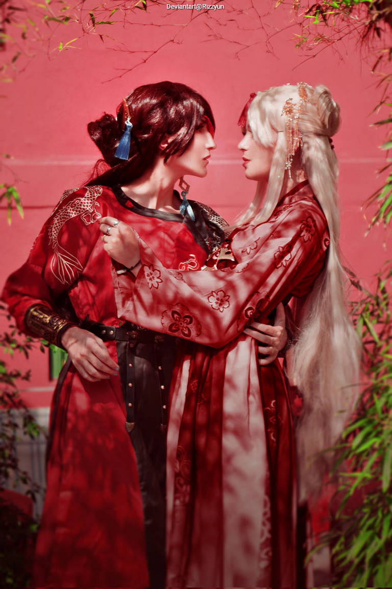A romantic scene featuring two individuals in traditional attire, one wearing a red robe with intricate designs and the other adorned in a flowing white garment, set against a vibrant pink backdrop with greenery.