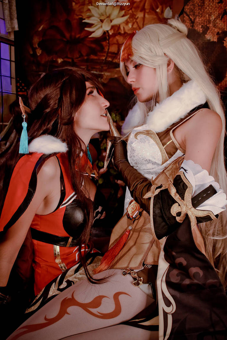Two women in elaborate cosplay costumes sharing an intimate moment in a beautifully decorated setting.