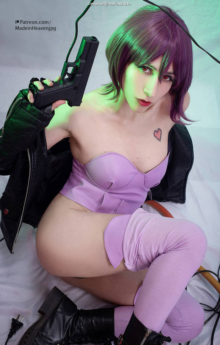A woman with short purple hair wearing a purple outfit poses with a gun, showcasing a confident expression. She is seated on the floor, wearing thigh-high stockings and combat boots, with a leather jacket draped over one shoulder.