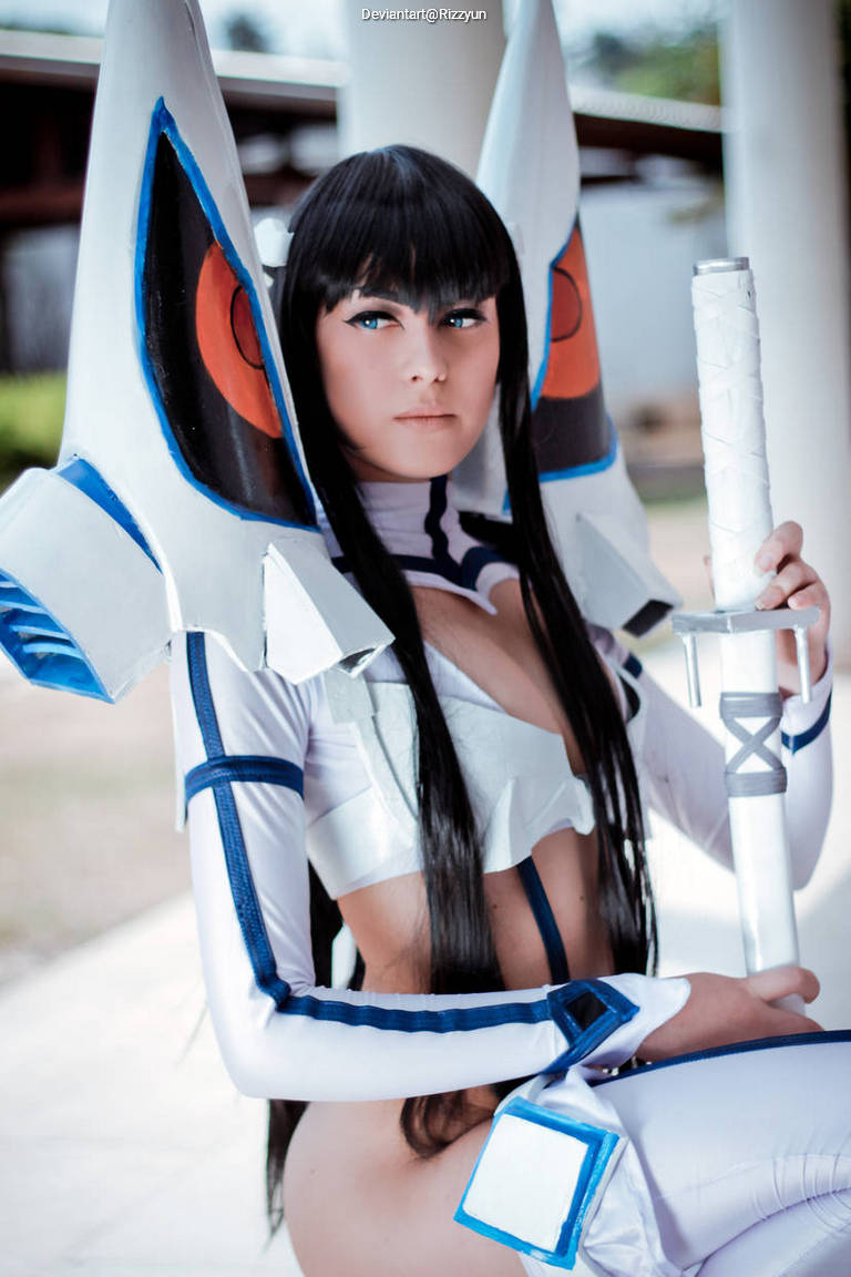 A person in a detailed costume with large ear-like accessories and blue accents, posing with a sword.