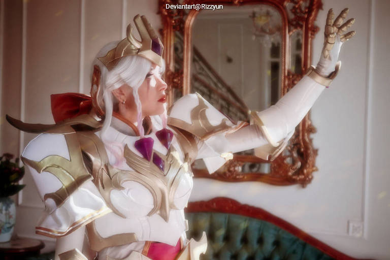 A person dressed in elaborate armor with a golden design and a red bow, striking a dramatic pose in an elegant interior.