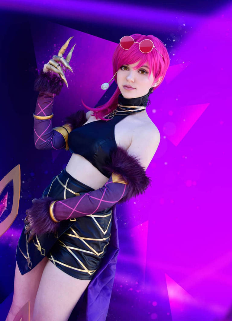 A person dressed in a black and gold outfit styled as a character, featuring pink hair, sunglasses, and claw-like accessories, posed against a vibrant purple background.