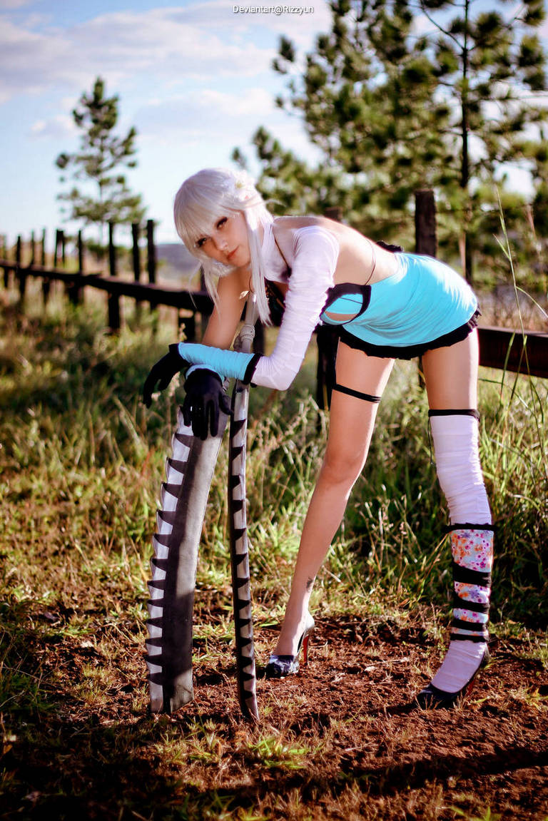 A person in a unique costume posing outdoors, leaning on a large sword against a background of trees and blue sky.