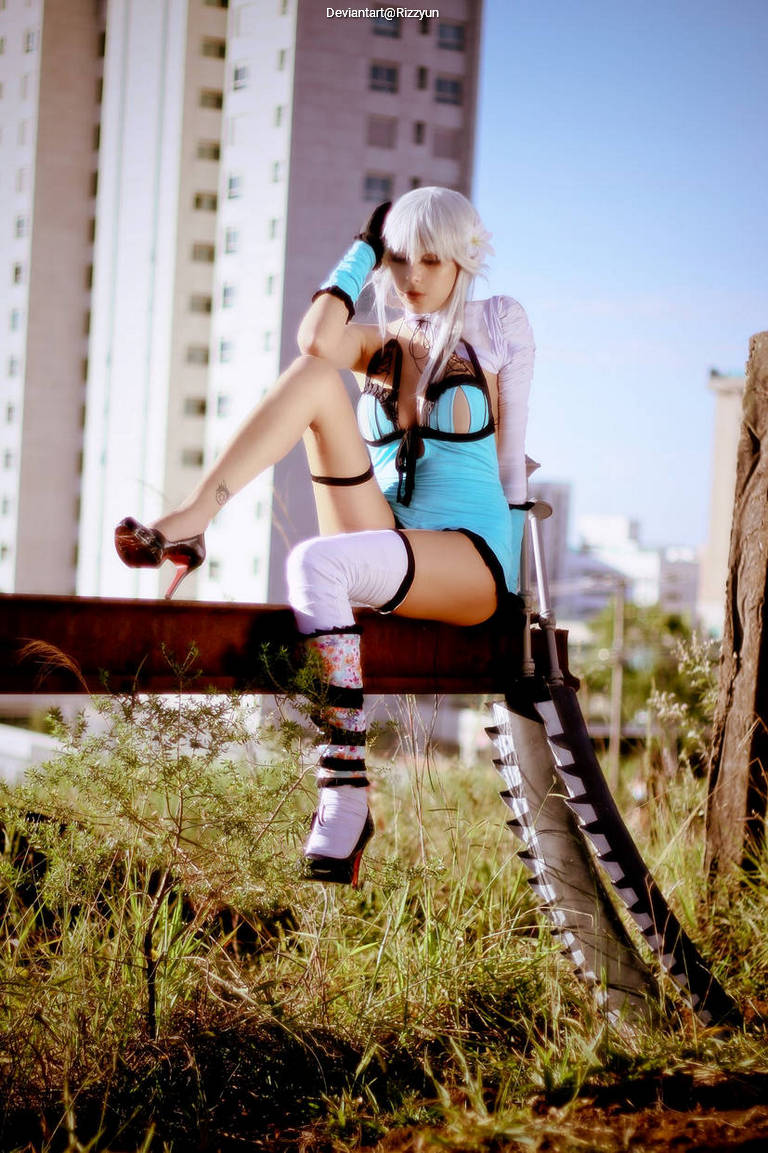 A person dressed in a blue and black outfit with white stockings sitting on a railing, with a large sword beside them in an outdoor setting.