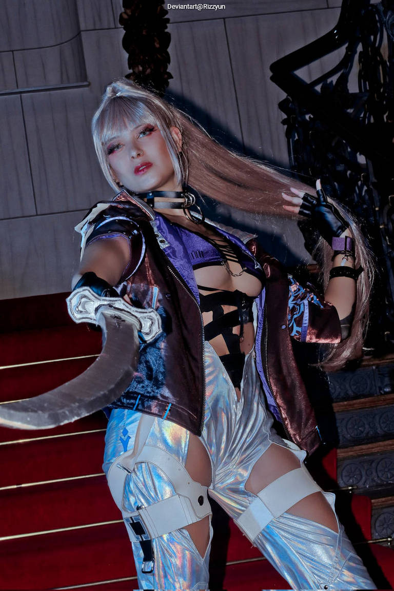 A person in a stylish, futuristic costume poses dramatically with a sword, featuring metallic and holographic elements. The background shows a grand staircase.