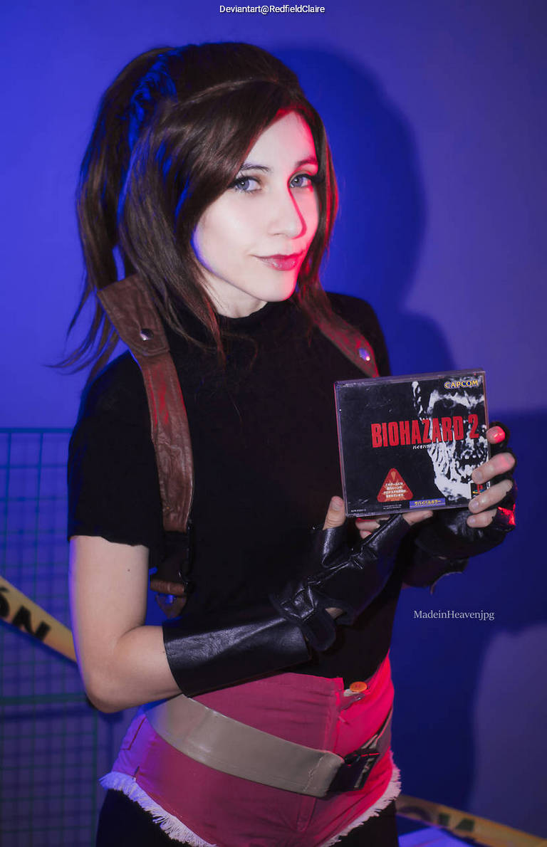 A person dressed in a cosplay outfit holds a video game titled 'BIOHAZARD 2' against a blue backdrop.