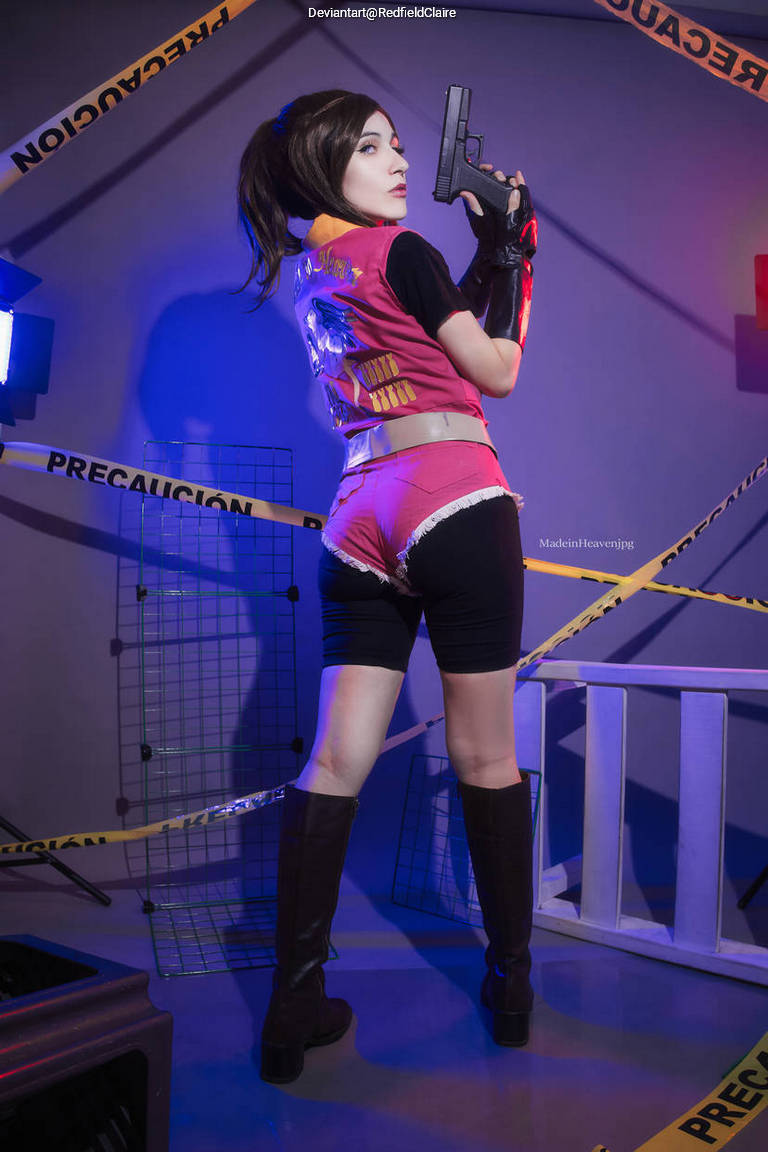 A person dressed in a character costume, facing away while holding a pistol, standing in a room with caution tape and metal grids.