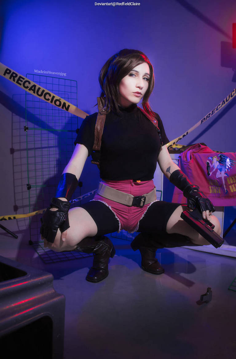 A woman in a black top and pink shorts poses in a crouched position, holding two handguns. The background features caution tape and dim lighting, creating a dramatic atmosphere.