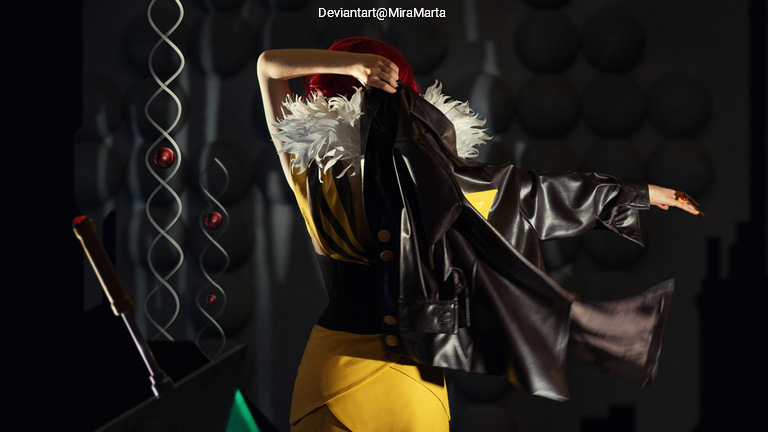 A person wearing a stylish yellow dress with feathers, partially turning away while holding a black leather jacket.