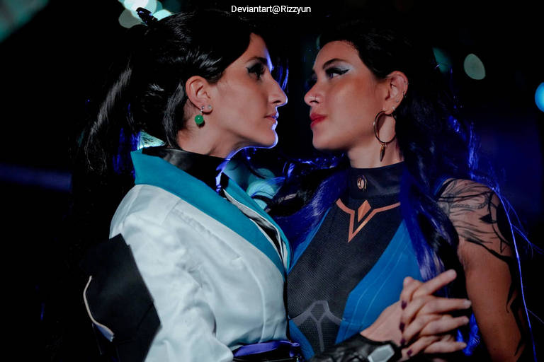 Two women in elaborate costumes engaging in an intense gaze, with dramatic lighting accentuating their features.