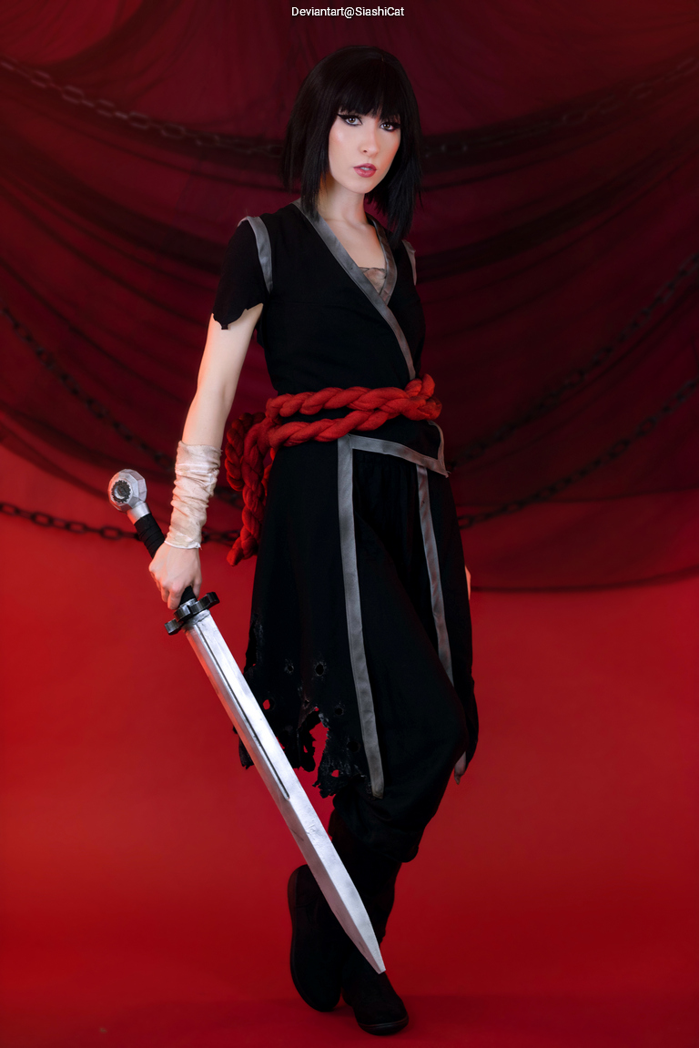 A person dressed in dark clothing wielding a sword, posed confidently against a red backdrop.