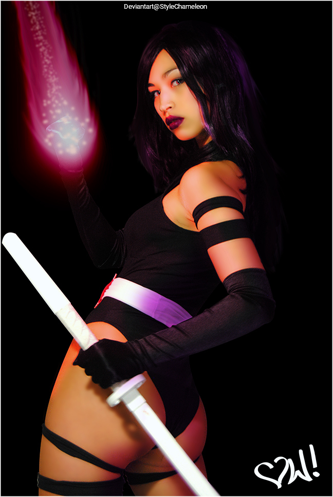 A woman in a black outfit with arm straps holds a glowing orb in one hand and a sword in the other. She has long hair and a confident expression, set against a dark background.
