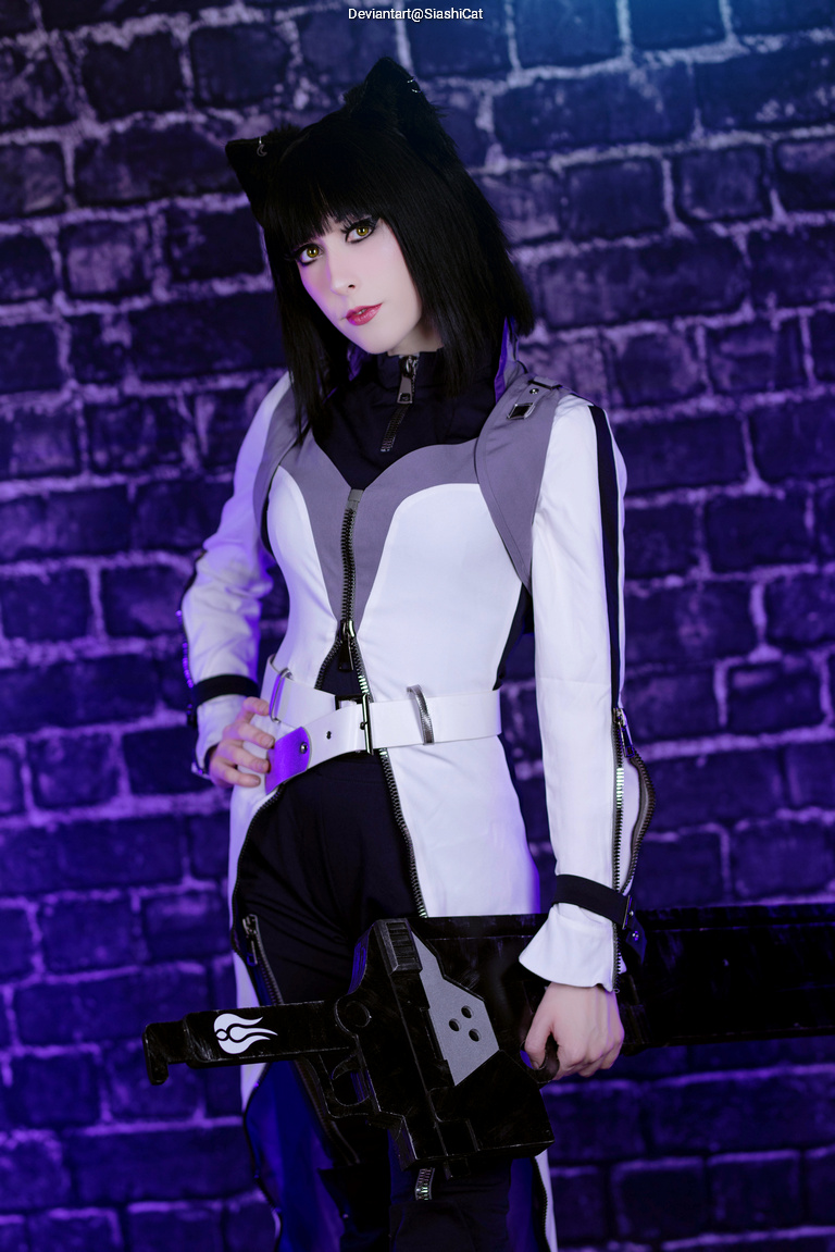 A person dressed in a white and black cosplay outfit with cat ears, holding a large weapon and posed against a brick wall with purple lighting.