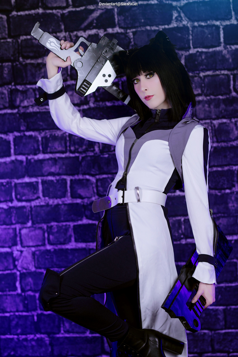 A person in a stylized costume holding a large futuristic weapon, posing against a dark brick wall with purple lighting.
