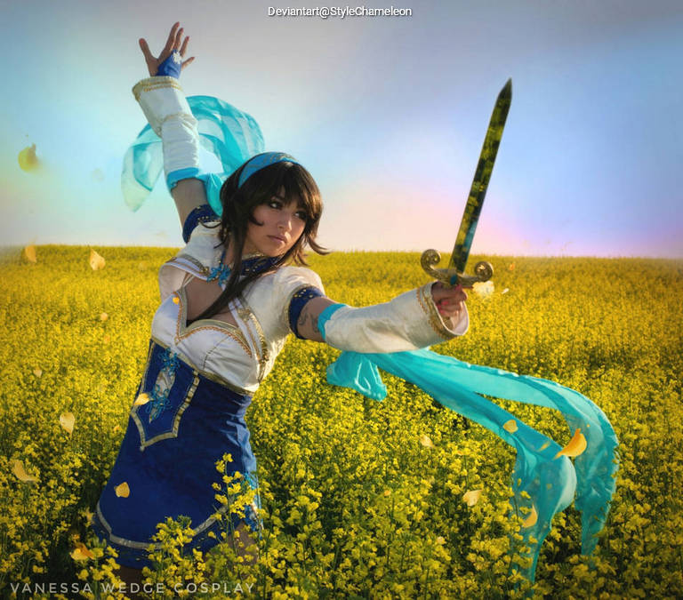 A person in a fantasy costume, holding a sword, standing in a yellow flower field with flowing ribbons around them.