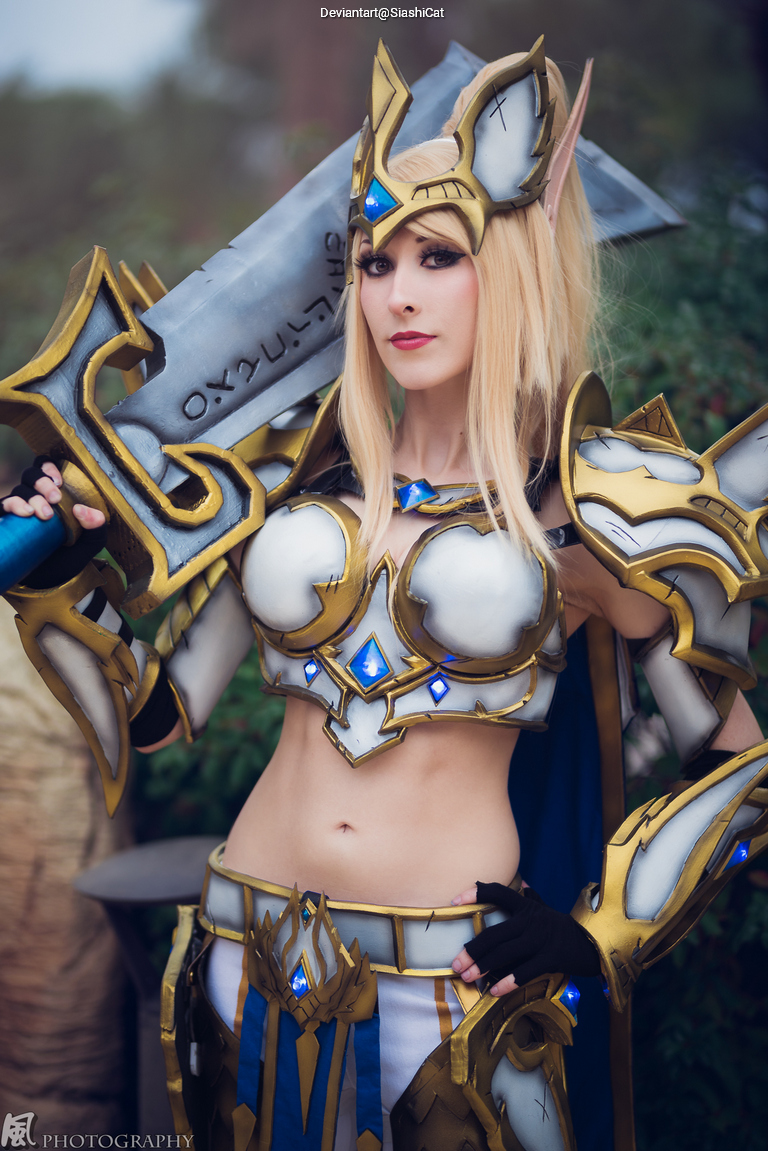 A person dressed in a fantasy armor costume with ornate designs and a large sword, posing confidently outdoors.