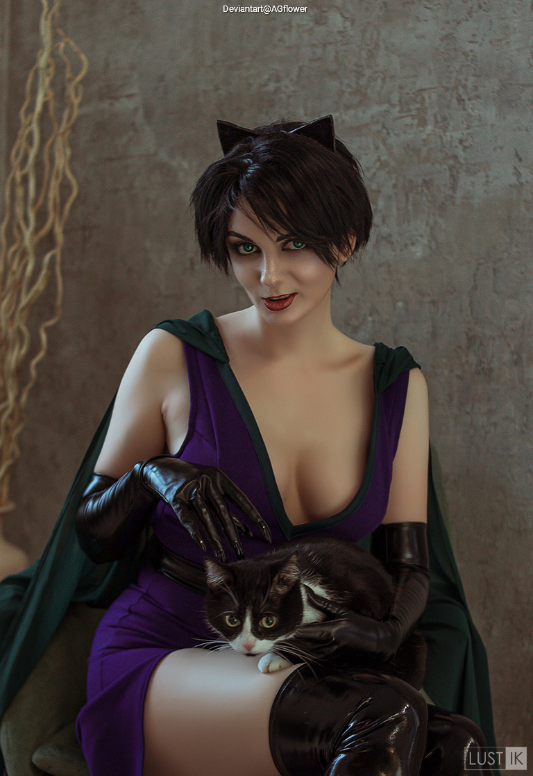 A woman dressed in a purple outfit and black gloves, with short dark hair and cat ears, sitting and holding a black and white cat.