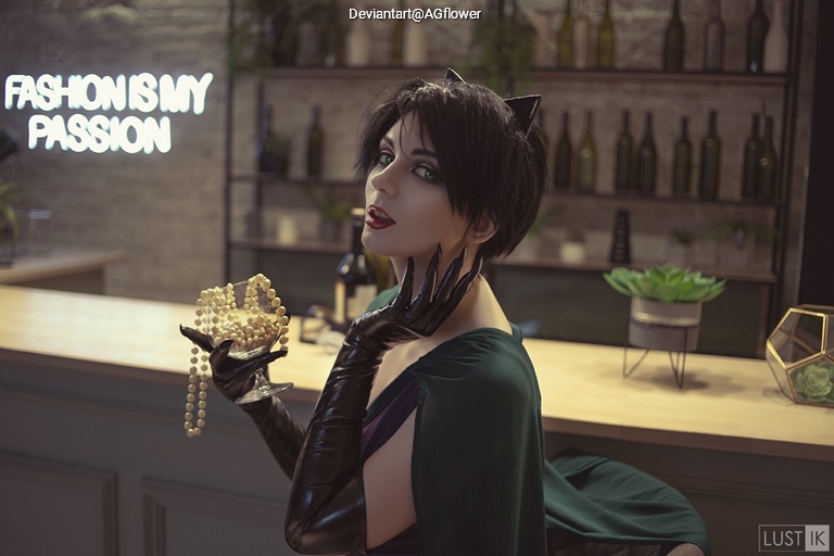 A person wearing a dark outfit and gloves, holding a string of pearls, poses in front of a sign that says 'FASHION IS MY PASSION' in a stylish setting.