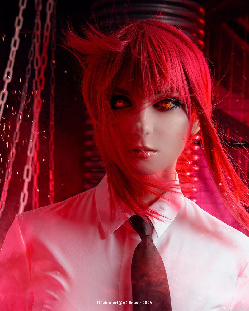 A character with red hair and striking orange eyes, wearing a white shirt and a black tie, set against a backdrop of chains and red lighting.