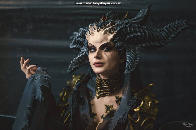 A person dressed in intricate cosplay with elaborate horned headpiece, showcasing dramatic makeup and a dark, detailed costume.