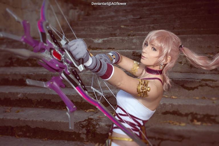 A person dressed in a costume resembling an archer, holding a colorful bow and aiming, set against a staircase background.