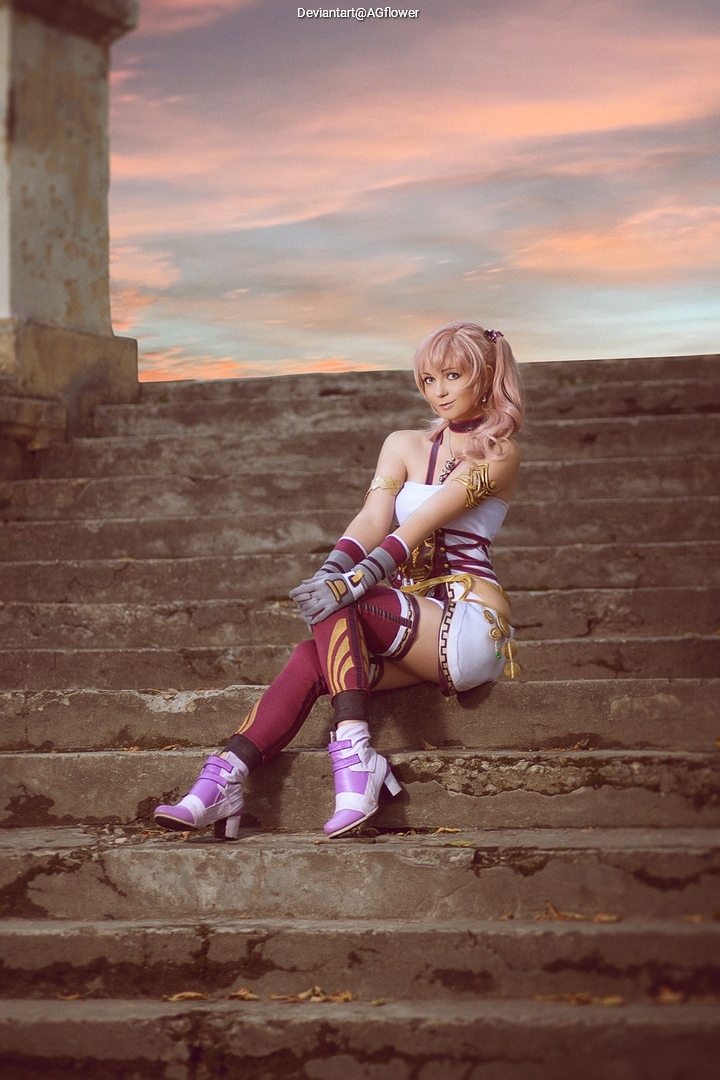 A person in a fantasy costume sitting on stone steps with a sunset in the background.