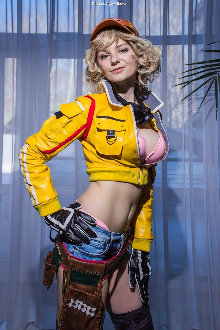 A person in a vibrant yellow jacket and denim shorts poses confidently, showcasing a playful fashion style in front of a bright background.