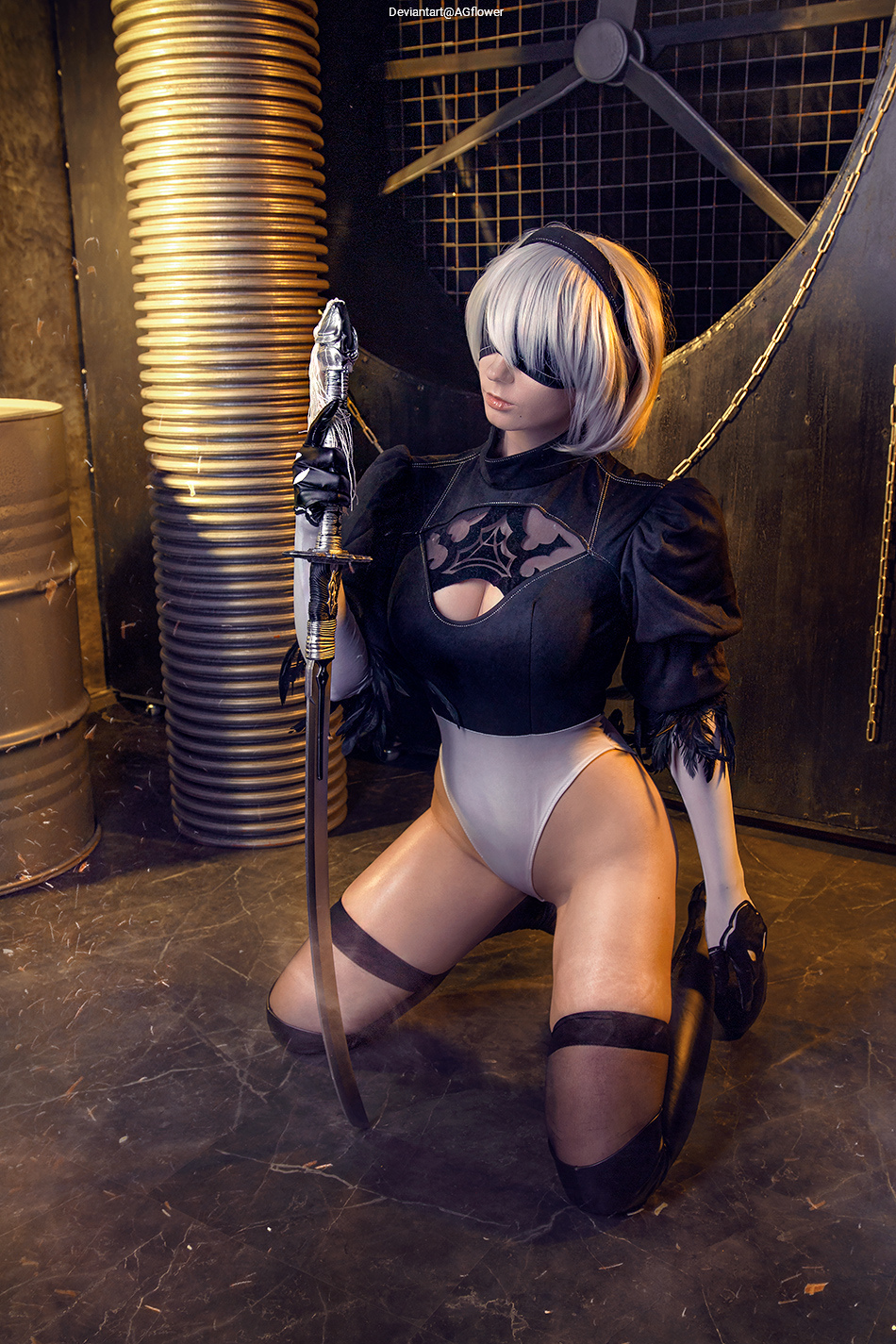A female cosplayer dressed as a character with short white hair, wearing a black outfit with lace and thigh-high stockings, kneeling while holding a sword in a dramatic pose.