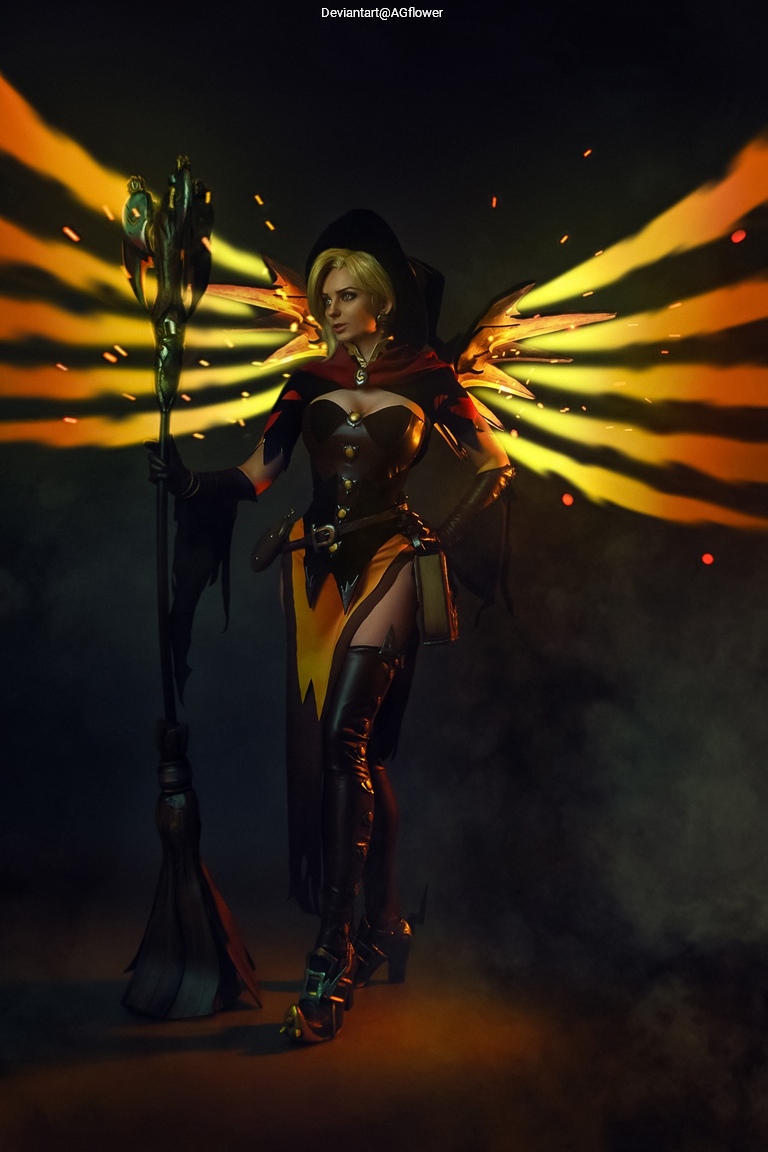 A character in a dramatic costume with black and yellow accents stands confidently, holding a staff and surrounded by striking wings. The background has a moody atmosphere with hints of smoke.