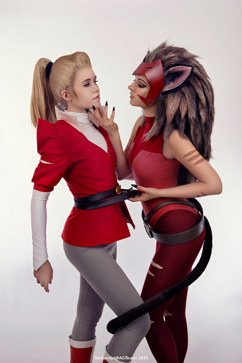 Two individuals in costume, one dressed in a red jacket and gray pants, and the other in a red outfit with animal features, posing close together with playful expressions.